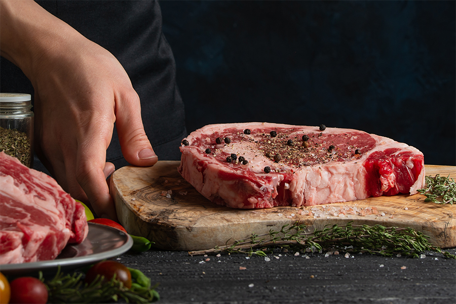 Steak auf Schneidebrett mit Gewürzen mariniert 